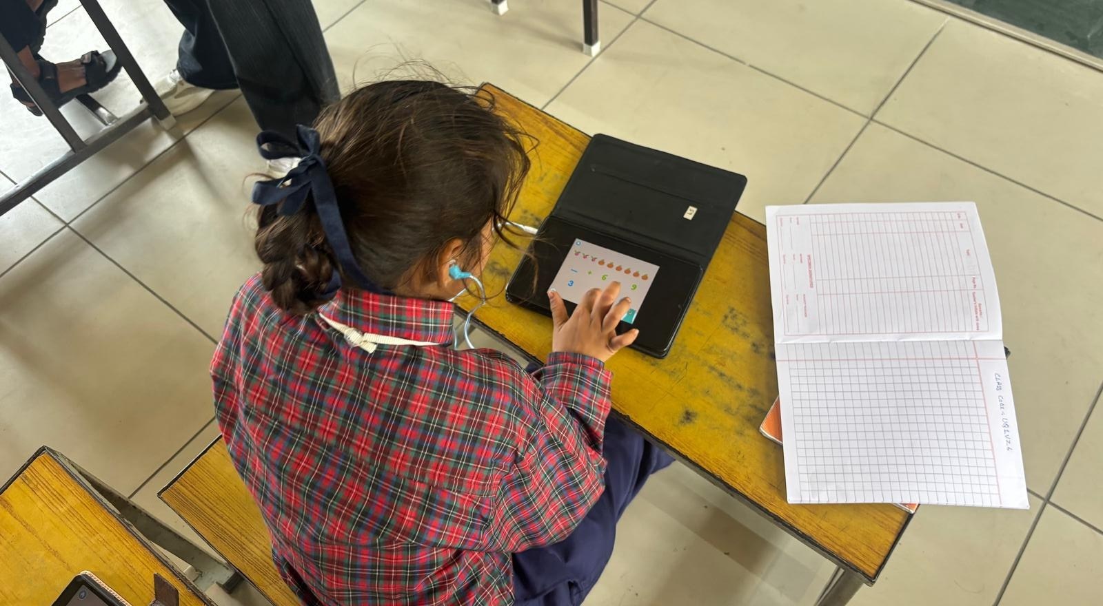 A student using a tablet for adaptive math practice at her desk